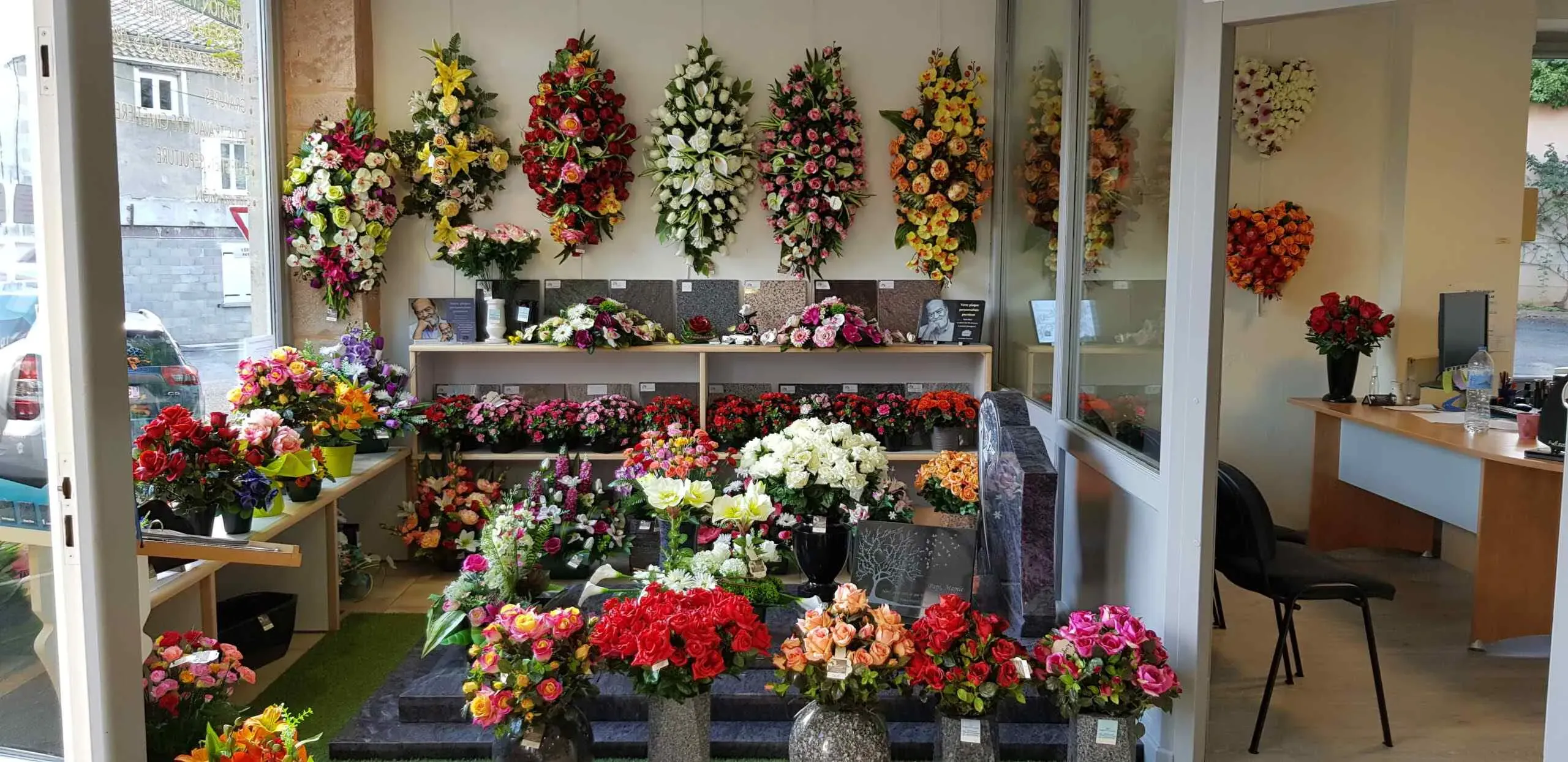 Exposition de fleurs artificielles, couronnes mortuaires et plaques funéraires en magasin de pompes funèbres