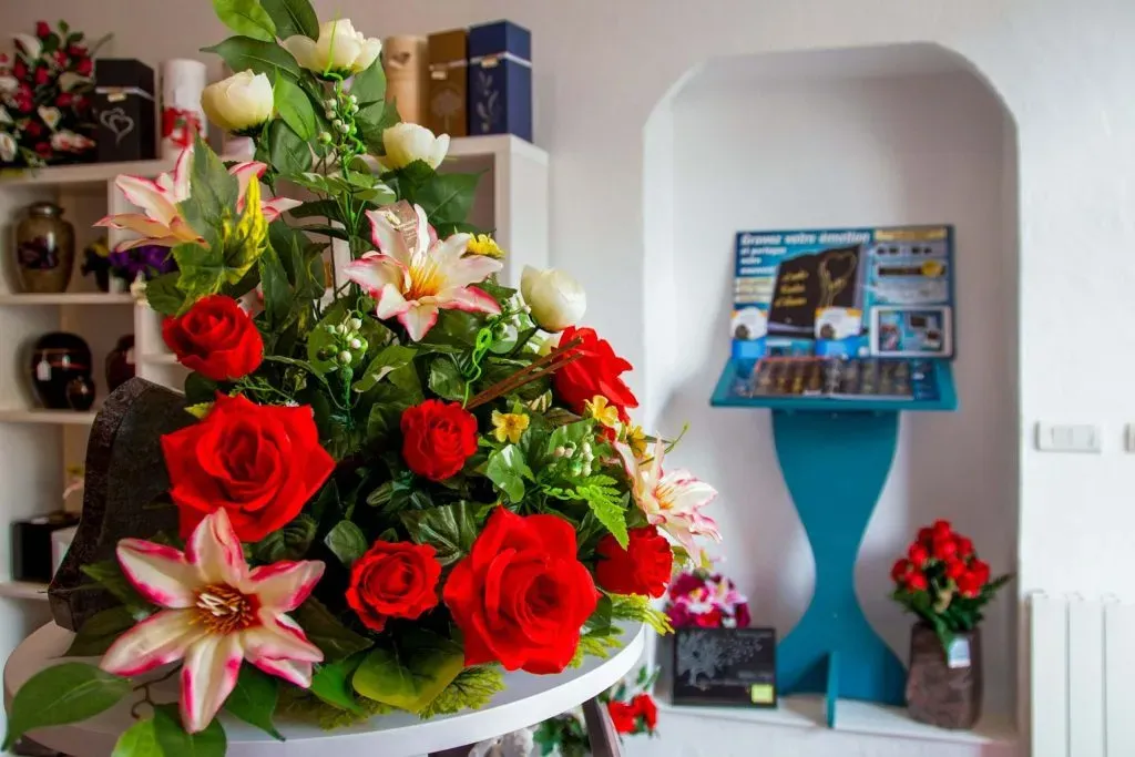Composition florale de deuil avec lillium et roses rouges exposée en agence funéraire
